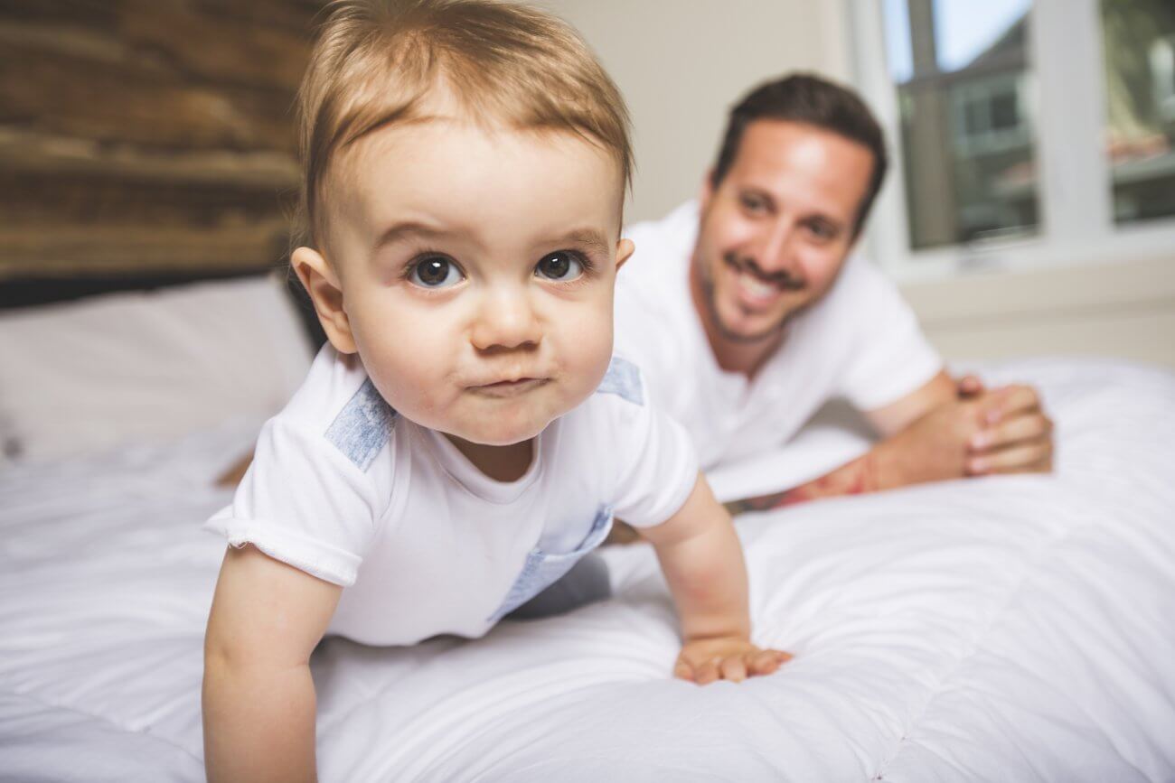 bebé jugando junto a su padre en la cama