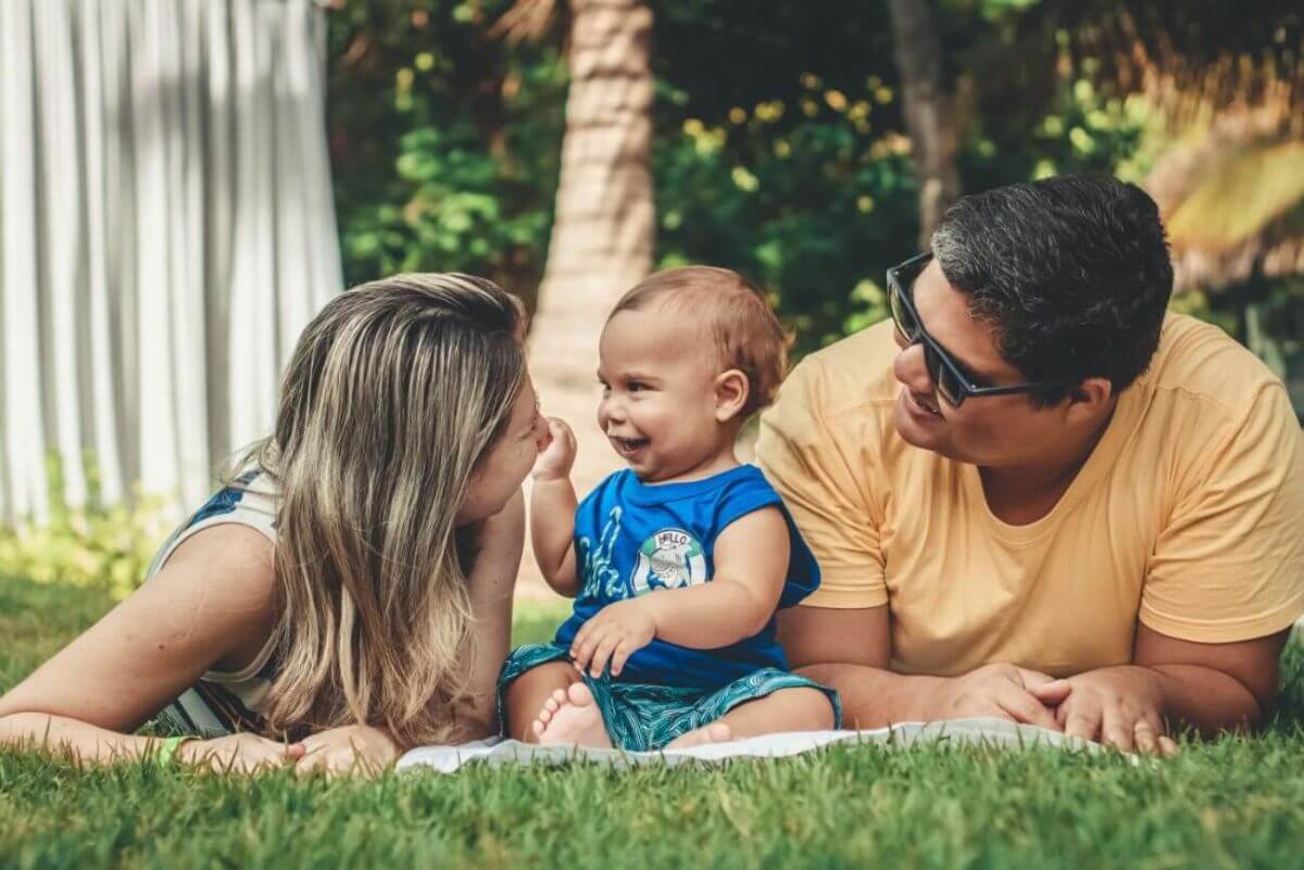 papás junto a su bebé jugando en el parqueé