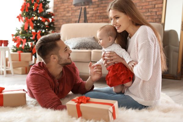 padres abriendo regalos de navidad con su bebé recién nacido